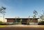 Sleek modern house with flat roof and natural stone accents, surrounded by landscaping, under a clear blue sky, exemplifying contemporary architecture design and eco-friendly building concepts.
