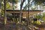 Modern minimalist house with large overhanging roof in a forest setting, blending contemporary architecture with nature, featuring extensive glass walls and outdoor balcony.