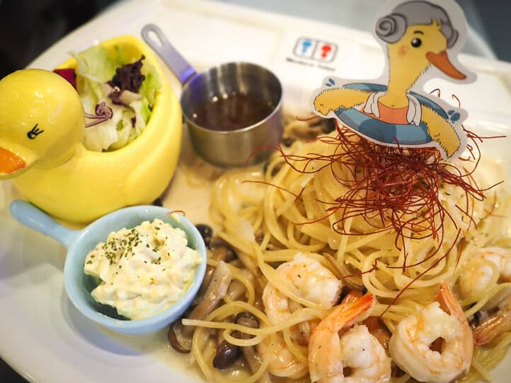 Un gran plato blanco con un montón de espaguetis con mariscos y algunas guarniciones pequeñas al lado.