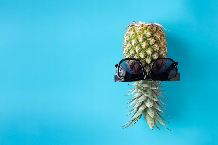 Upside down pineapple on a blue background with sunglasses