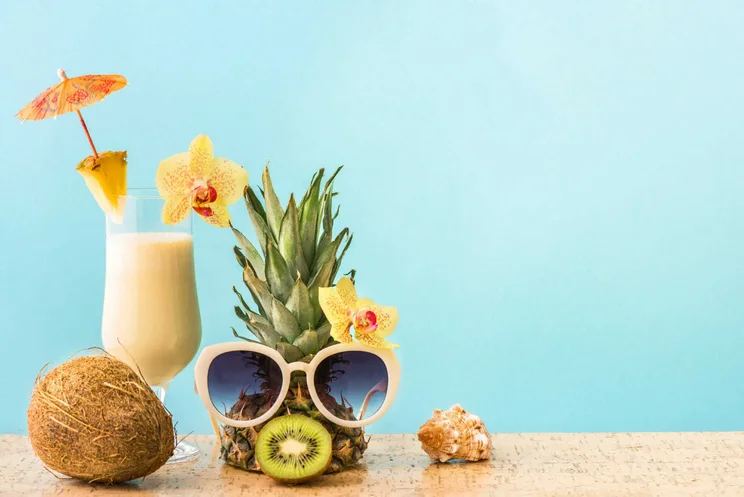 pineapple with sunglasses next to pina colada