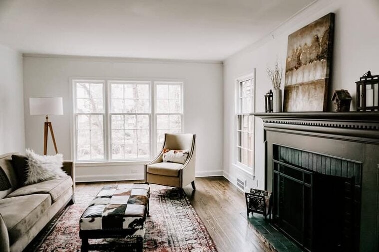 Modern minimalist living room with large windows, cozy armchair, and elegant fireplace showcasing contemporary interior design.