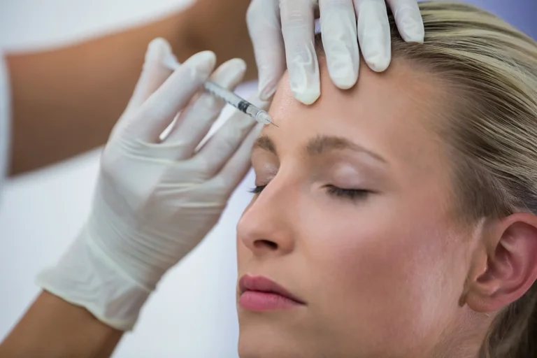 Close-up of a woman receiving an aesthetic injection in her forehead, illustrating cosmetic treatments and how long dermal fillers last.