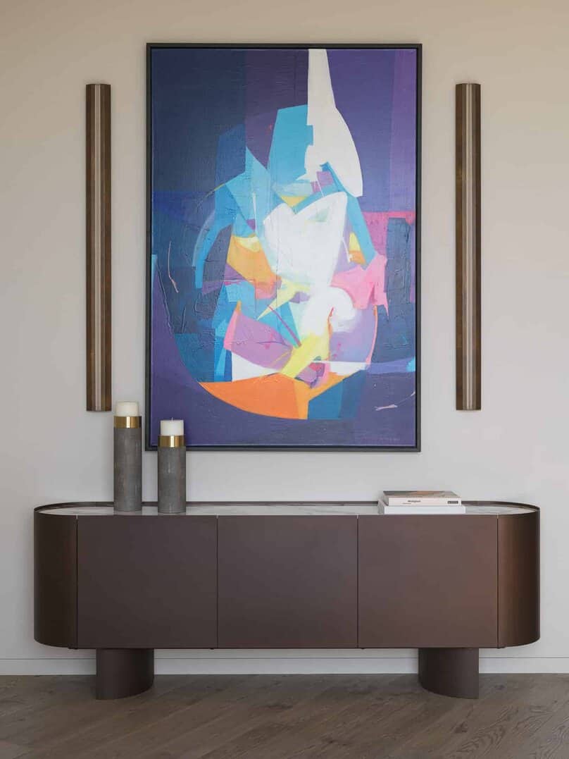Modern sideboard with bold abstract painting and vertical sconces.