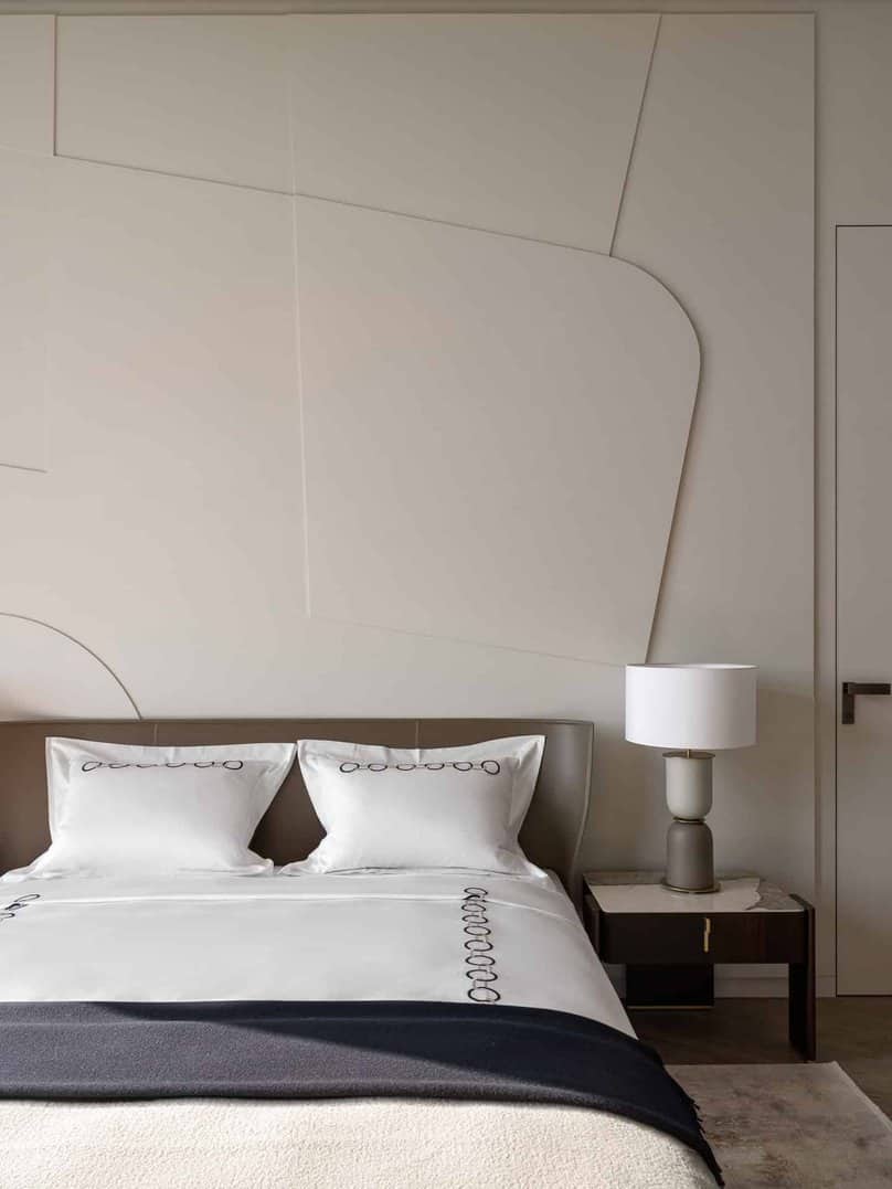 Close-up view of upholstered bed with textured wall in the background.