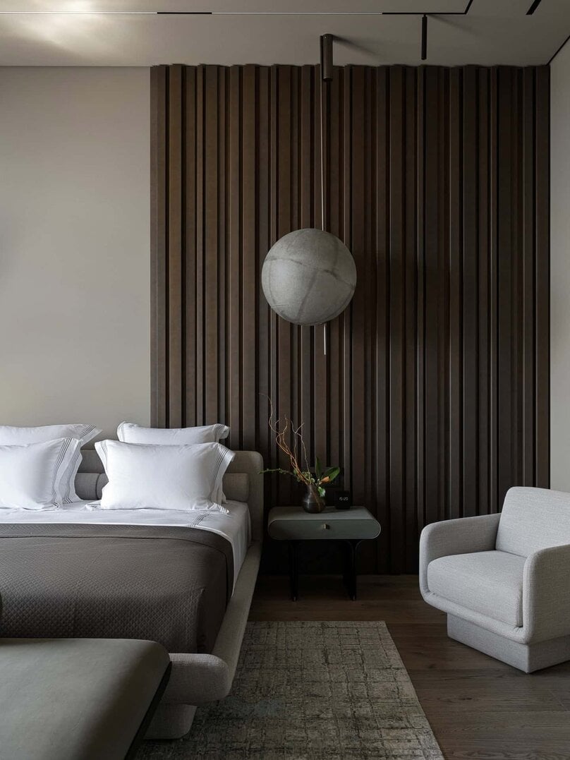 Detailed view of wall paneling and suspended sconce in elegant bedroom.