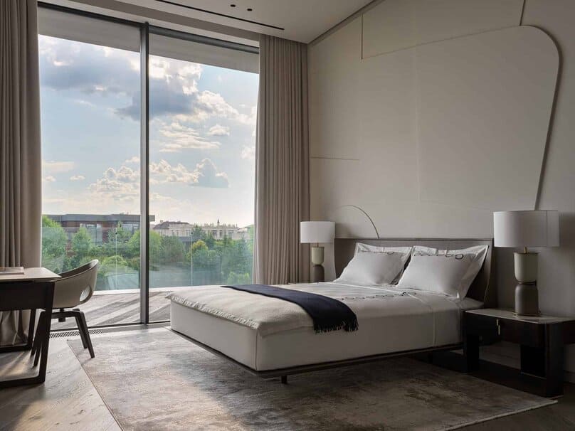 Spacious bedroom with serene view through floor-to-ceiling glass doors.