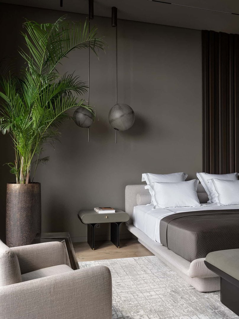 Modern bedroom with globe pendant lights and a tall planter beside the bed.