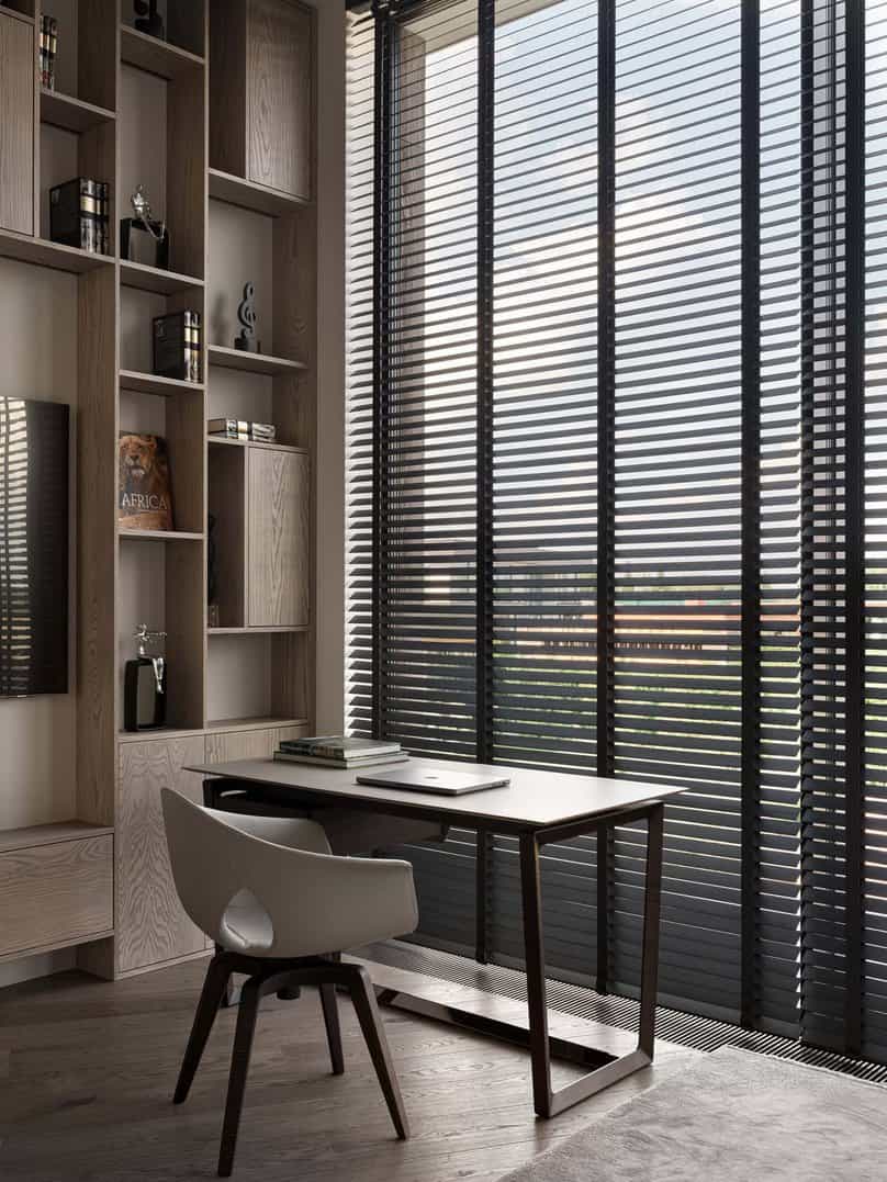 Minimal home office with a compact desk and tall windows covered by blinds.