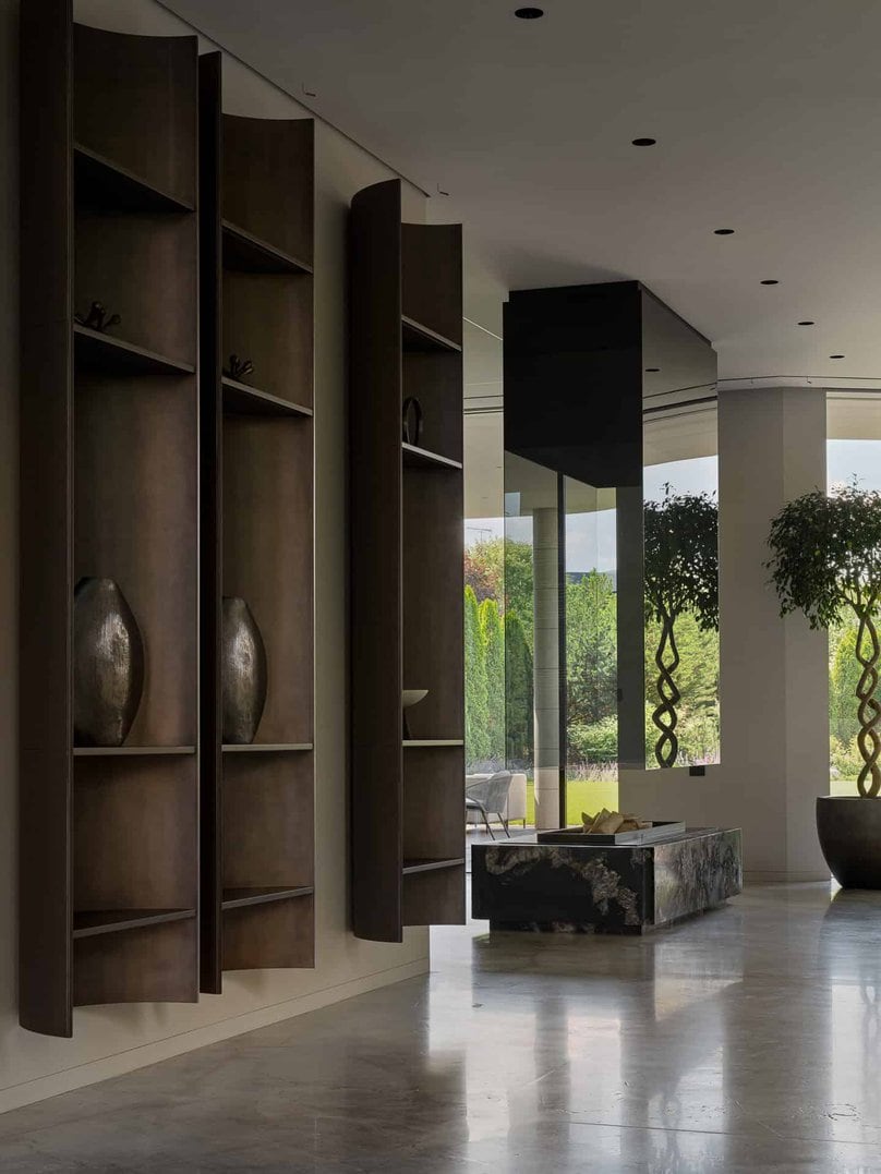 Minimalist interior with sculptural floating shelves and outdoor garden view.