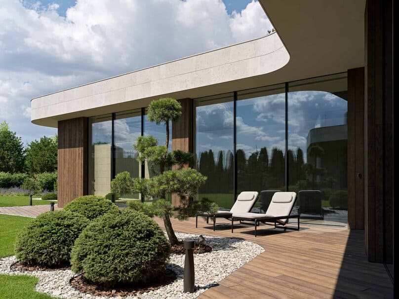 Modern exterior view of home with curved roof and bonsai-inspired landscaping.