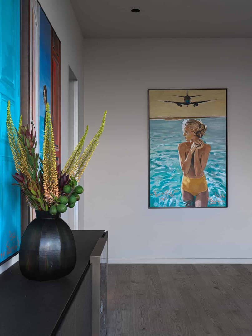 Bright hallway featuring colorful portrait paintings and floral arrangement.