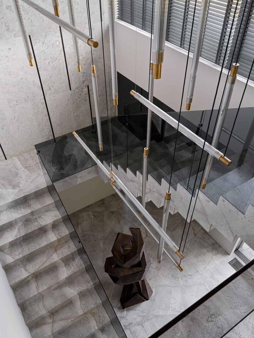 Sculptural lighting installation suspended above modern staircase.