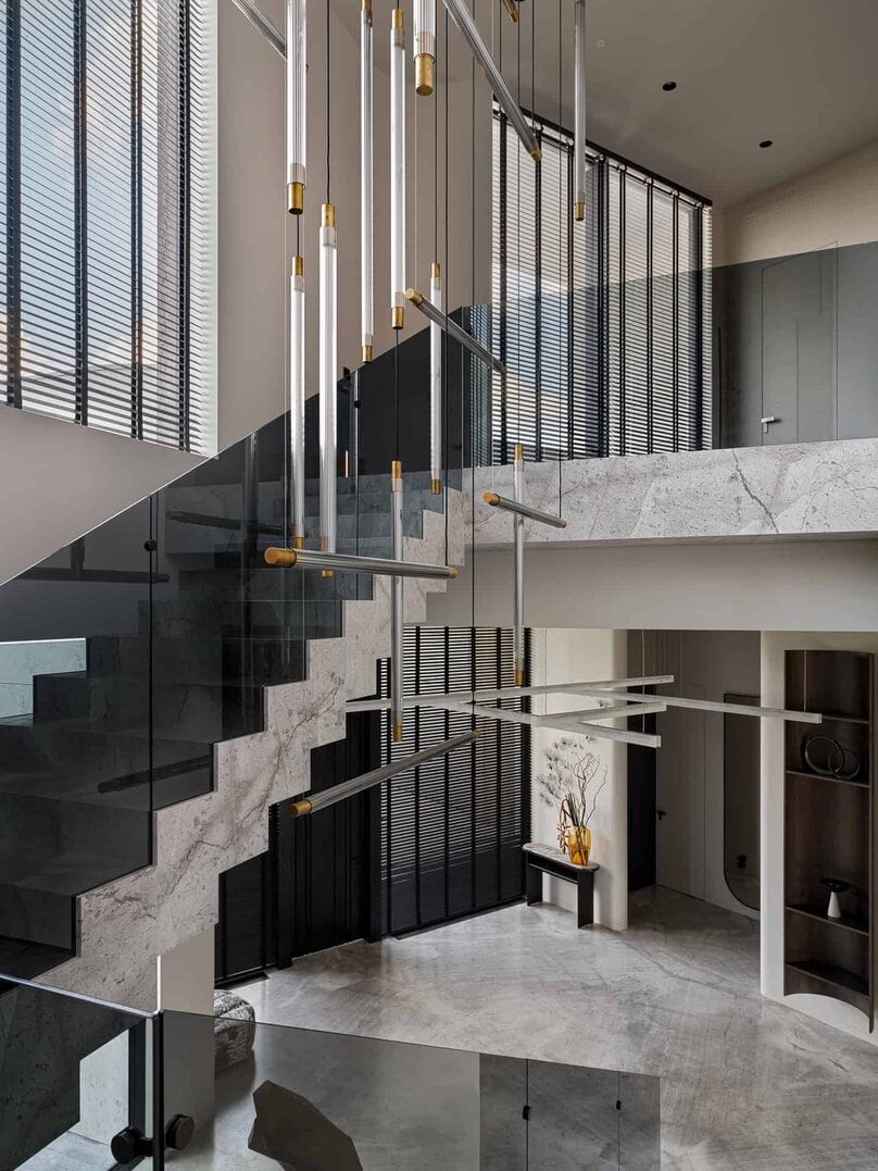 Modern chandelier installation suspended over open staircase.