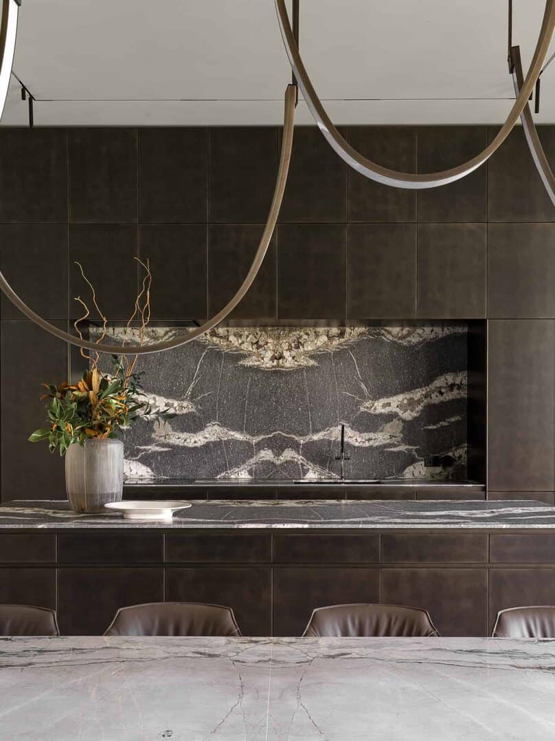Detailed view of elegant marble backsplash and dark cabinetry in kitchen.