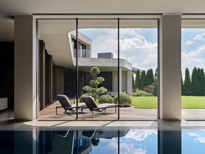 Two sun loungers placed in front of glass doors opening to garden from pool room.