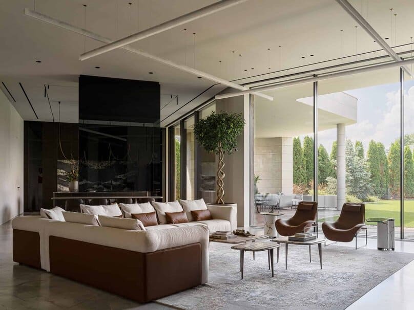 Luxury living room with plush sofa and expansive garden view through glass walls.