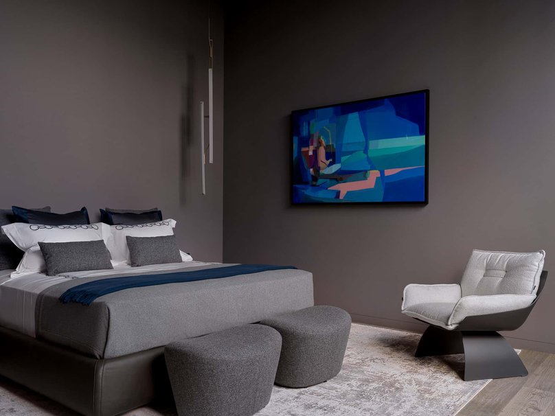 Minimalist bedroom with monochrome tones and striking abstract blue painting.