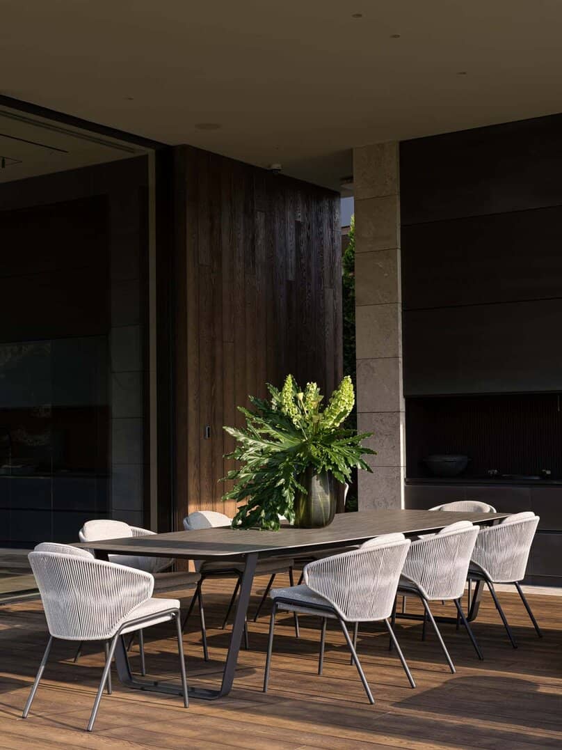 Outdoor dining area with modern chairs and flower arrangement on wooden deck.