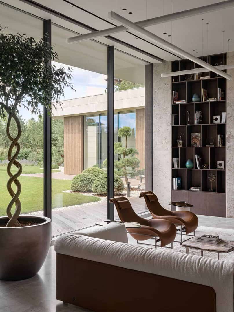 Cozy reading nook with designer chairs and full-height windows facing the garden.