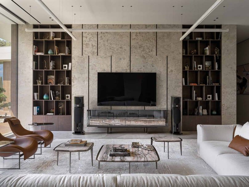 Contemporary TV wall with integrated dark shelving and textured stone backdrop.