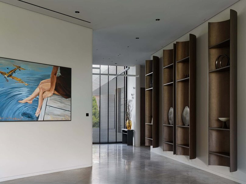 Artfully styled wall shelves and a colorful painting in a modern hallway.