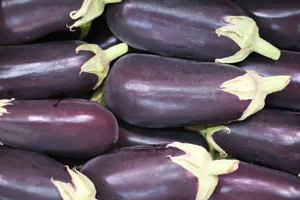 Berenjenas orgánicas frescas, destacando su color profundo y textura brillante, ideales para cocinar en recetas saludables y sostenibles, cultivadas de forma ecológica en huerto.bio.