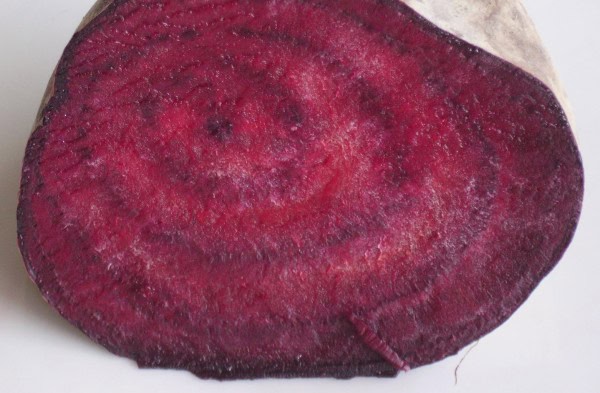 Zanahoria morada orgánica cortada por la mitad en vista cercana, resaltando su color intenso y textura natural, cultivada de forma ecológica en Huerto.Bio.