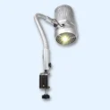 The Sunflower II LED Nail Dust Collector features a silver, flexible-arm LED light with a vented cylindrical head that emits a bright yellow beam. It attaches securely to surfaces with a sturdy metal clamp, shown against a pale blue background. Read more at Aerovex Systems (aerovexsystems.com)