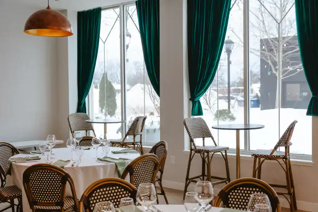 Cozy dining area at The Ember Room with elegant tables and green curtains.