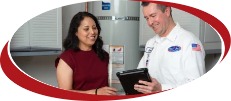 A friendly, background-checked Bell Brothers technician reviews clear, upfront pricing with a customer by a water heater—No Surprise Guarantee.