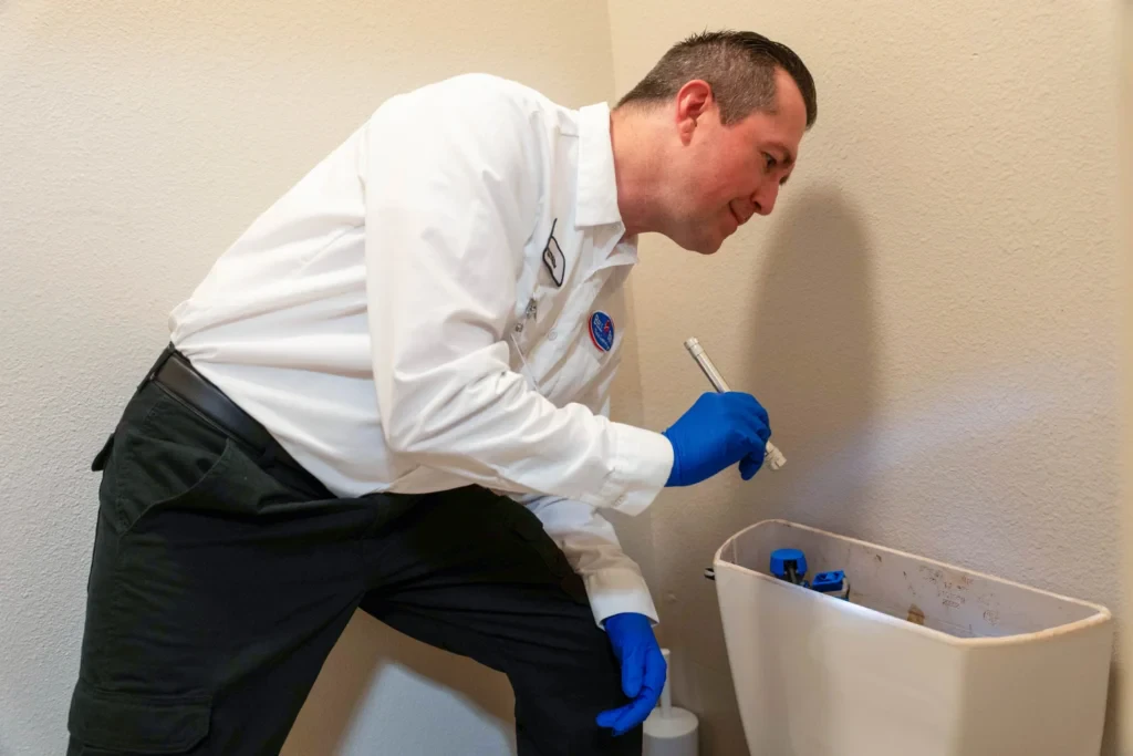 A trusted Bell Brothers tech in gloves inspects a toilet tank, ensuring quality, no surprises, and upfront pricing for Sacramento homes.