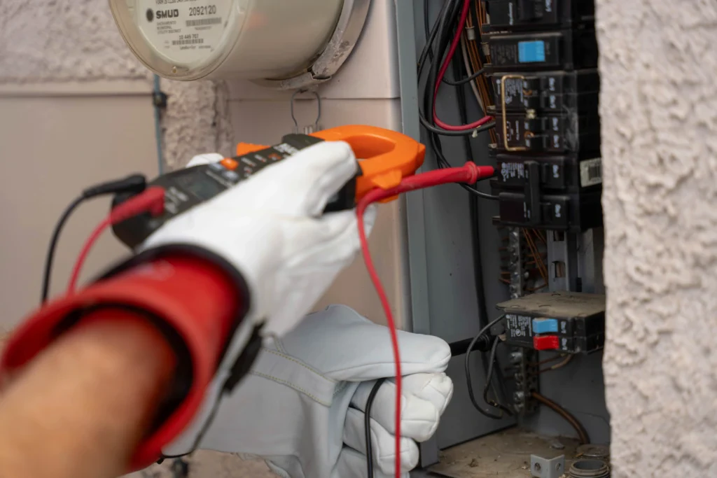 A Bell Brothers tech in safety gloves tests circuit wiring, reflecting our upfront pricing, trusted service, and No Surprise Guarantee.