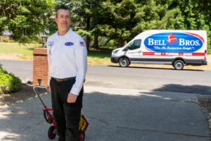 A trusted, background-checked Bell Bros. tech with leak tools stands by a service van, showcasing our No Surprise Guarantee.