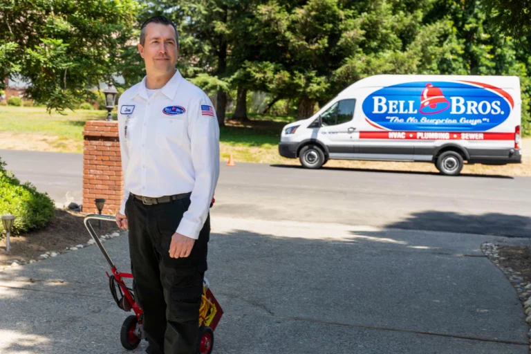 A trusted, background-checked Bell Bros. tech with leak tools stands by a service van, showcasing our No Surprise Guarantee.