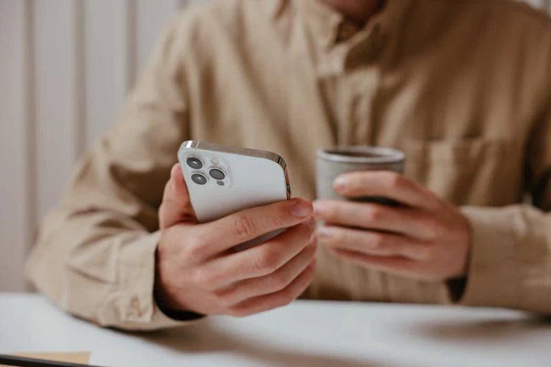 Man checking a dating app on his phone while holding a coffee cup