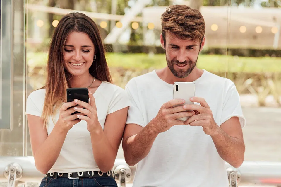 Adult Friend Finder vs Tinder 2025 comparison – two persons holding phones, they are side by side smiling