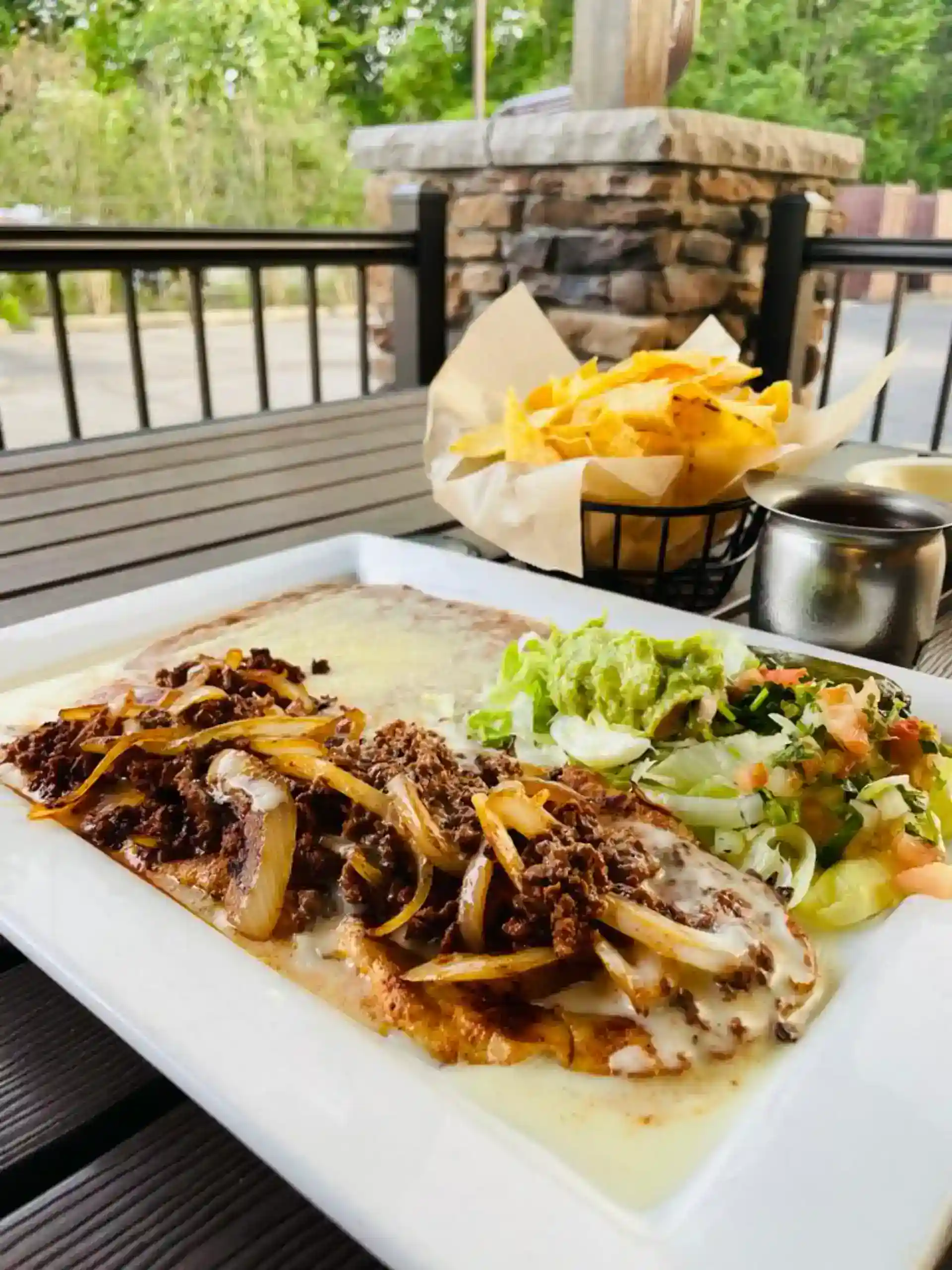 Mexican dish with beef, onions, and cheese served with fresh salad and fries.