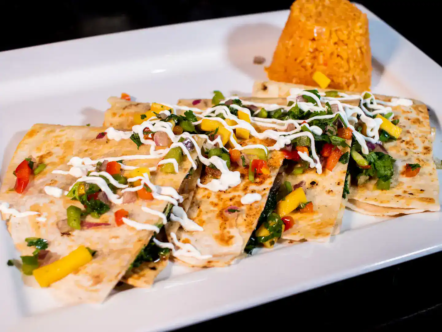Delicious chicken quesadillas with colorful vegetables and sour cream drizzle.