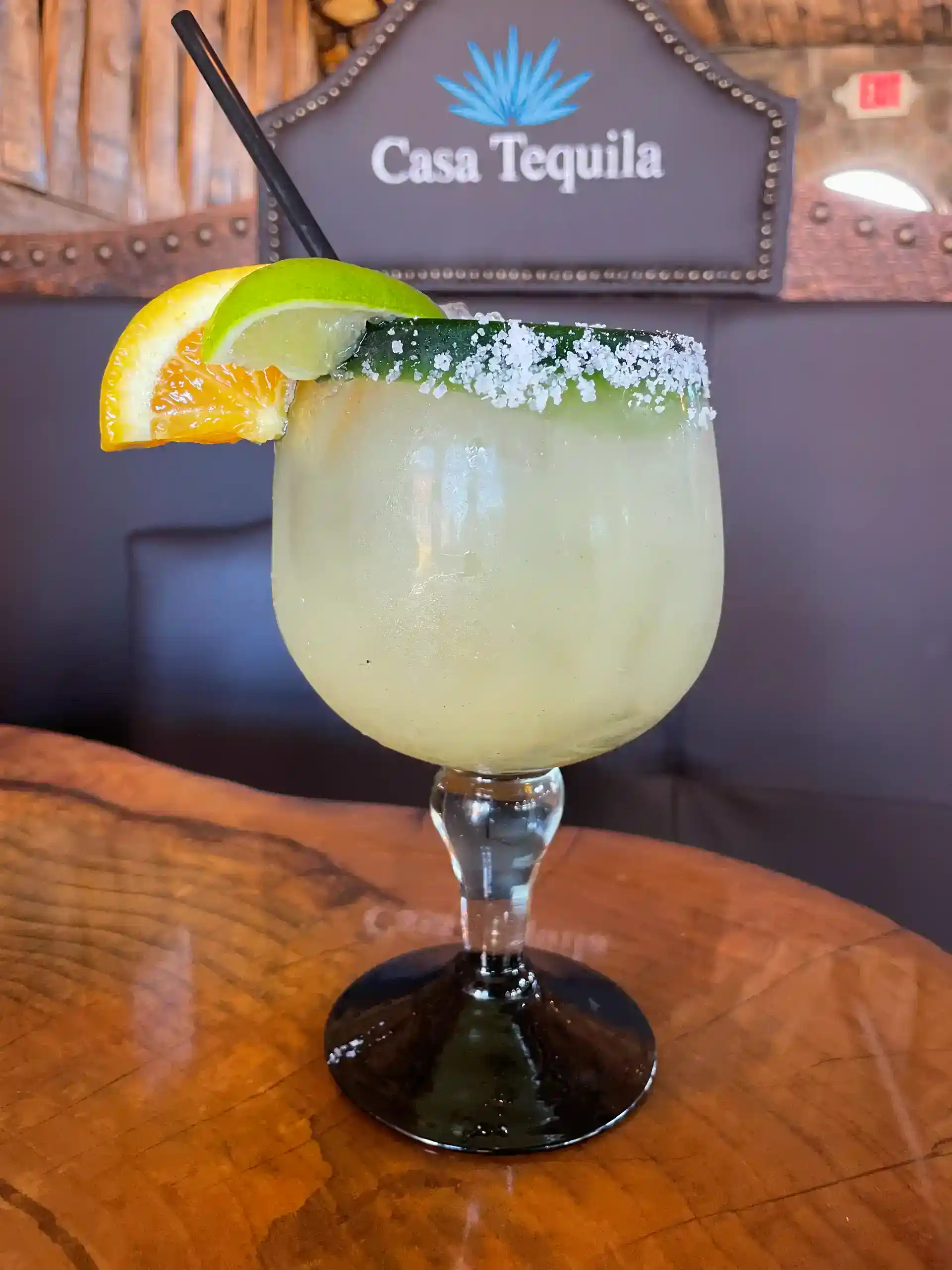 Refreshing margarita with lime and orange slices on a wooden table.