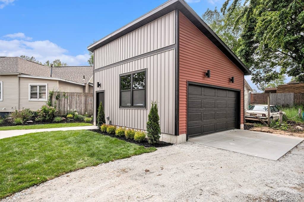 Contemporary garage with metal siding and black garage door in a residential yard.