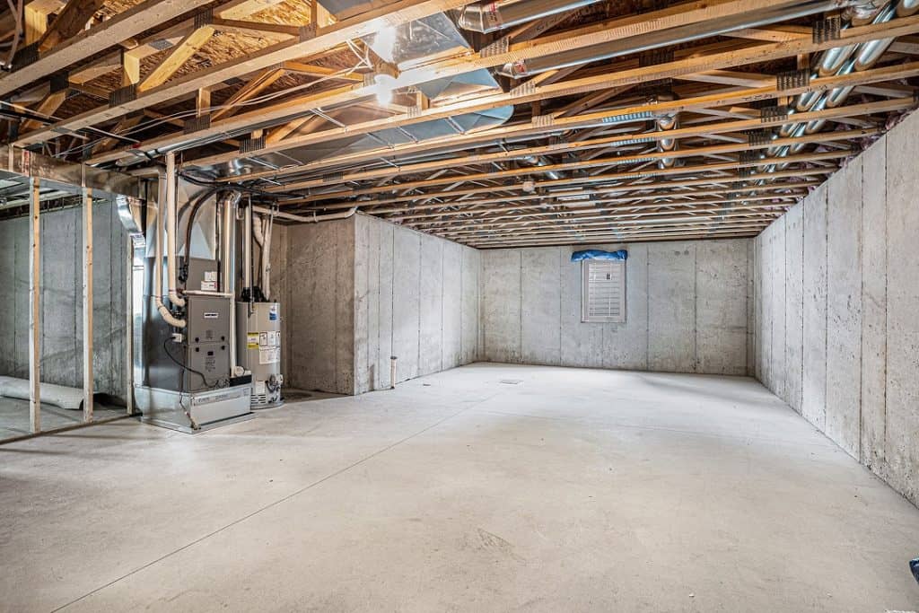 Unfinished basement with exposed ceiling and concrete walls.