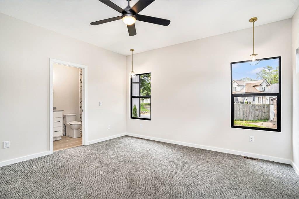 Bright modern bedroom with large windows and ceiling fan.