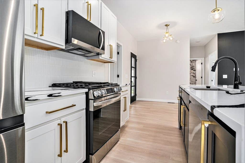 Contemporary kitchen with white cabinets, black accents, and stainless steel appliances.