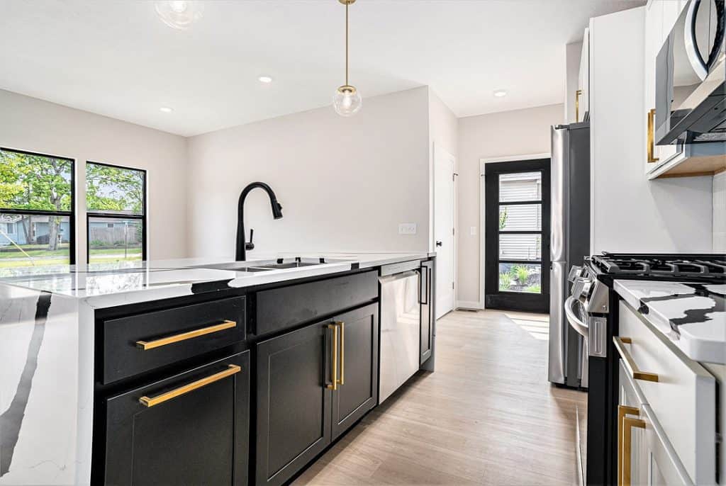 Contemporary kitchen with black cabinets, white countertops, and stainless steel appliances.