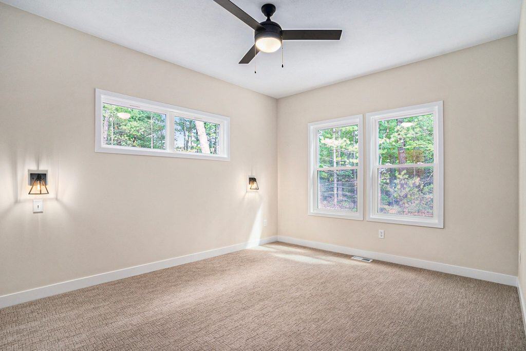 Bright, spacious bedroom with large windows and ceiling fan.