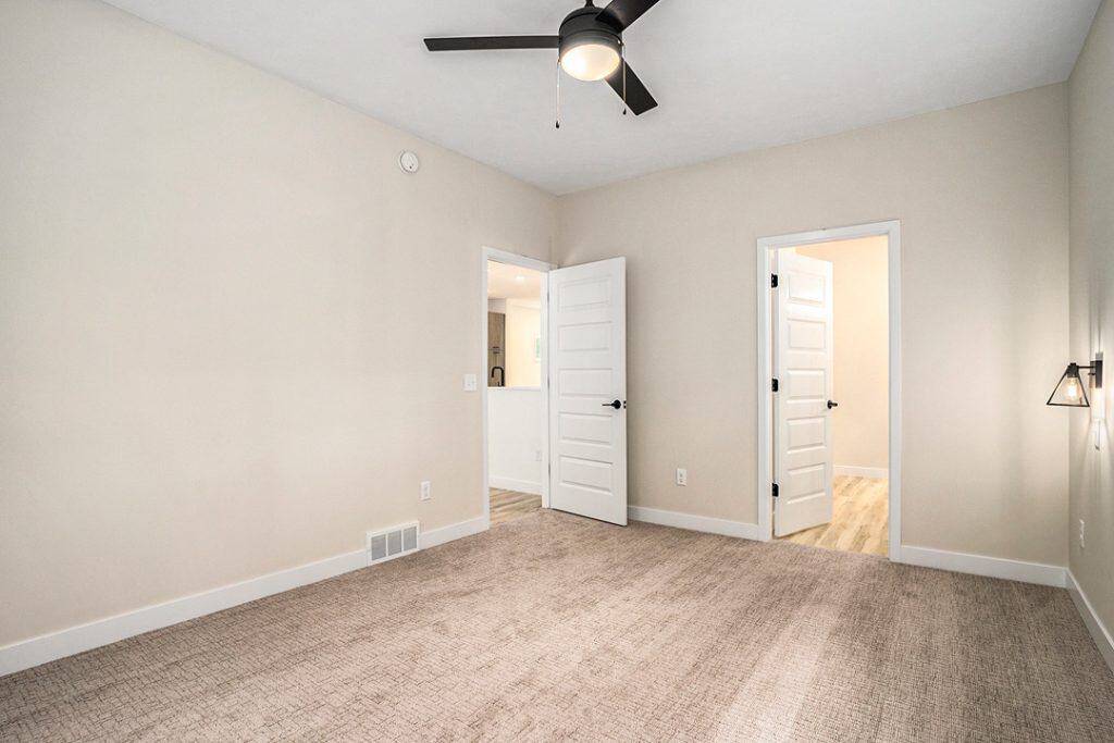 Spacious, modern room with neutral walls and ceiling fan.