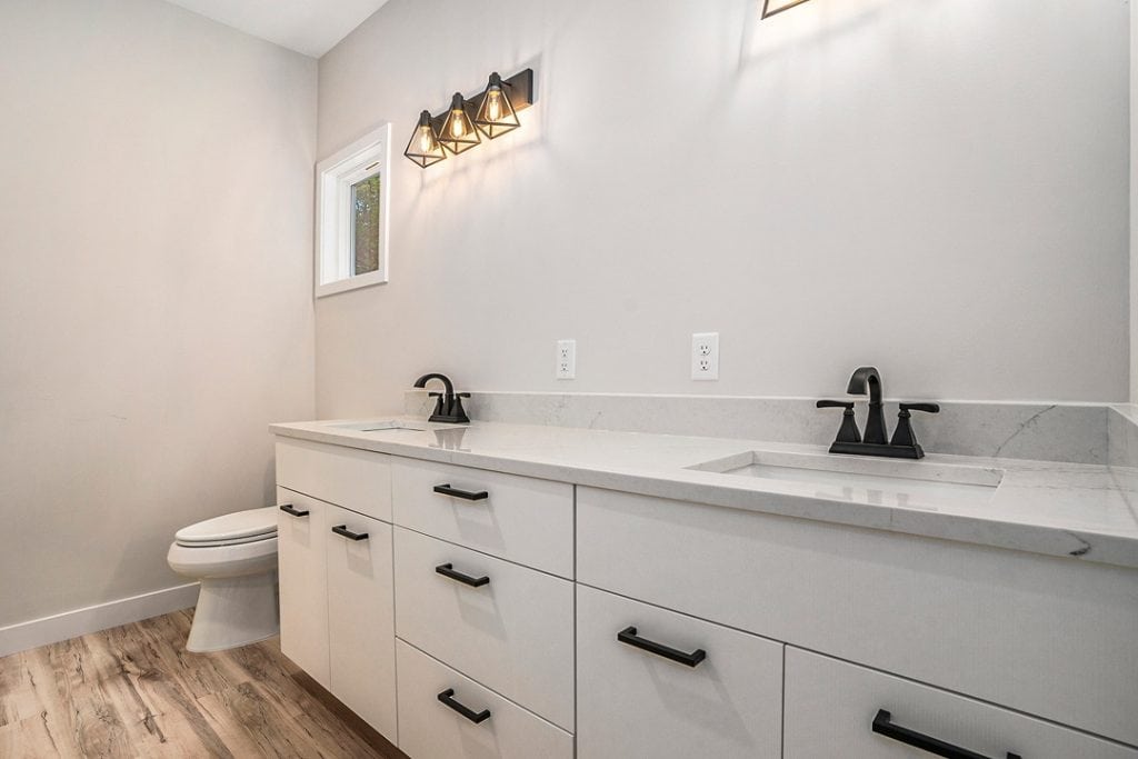 Contemporary bathroom with double sinks, white cabinetry, and stylish lighting fixtures.
