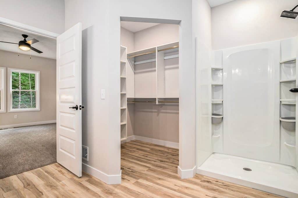 Spacious walk-in closet with built-in shelves and a modern shower stall.