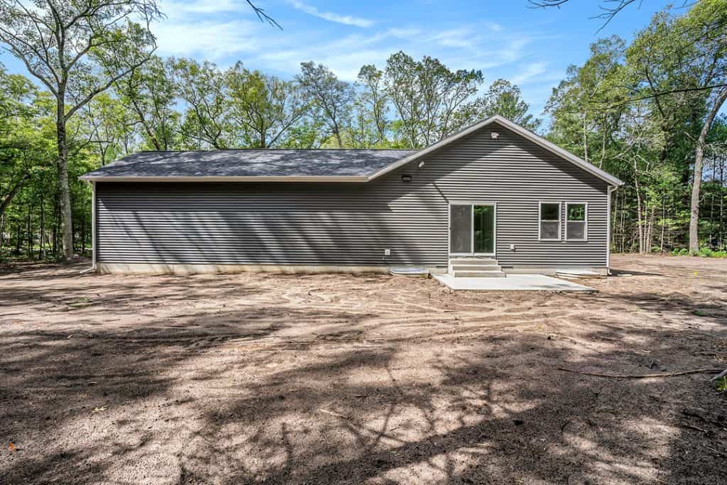 Modern new home with gray siding and large backyard in development.